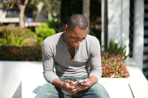 young African-American man texting on a phone